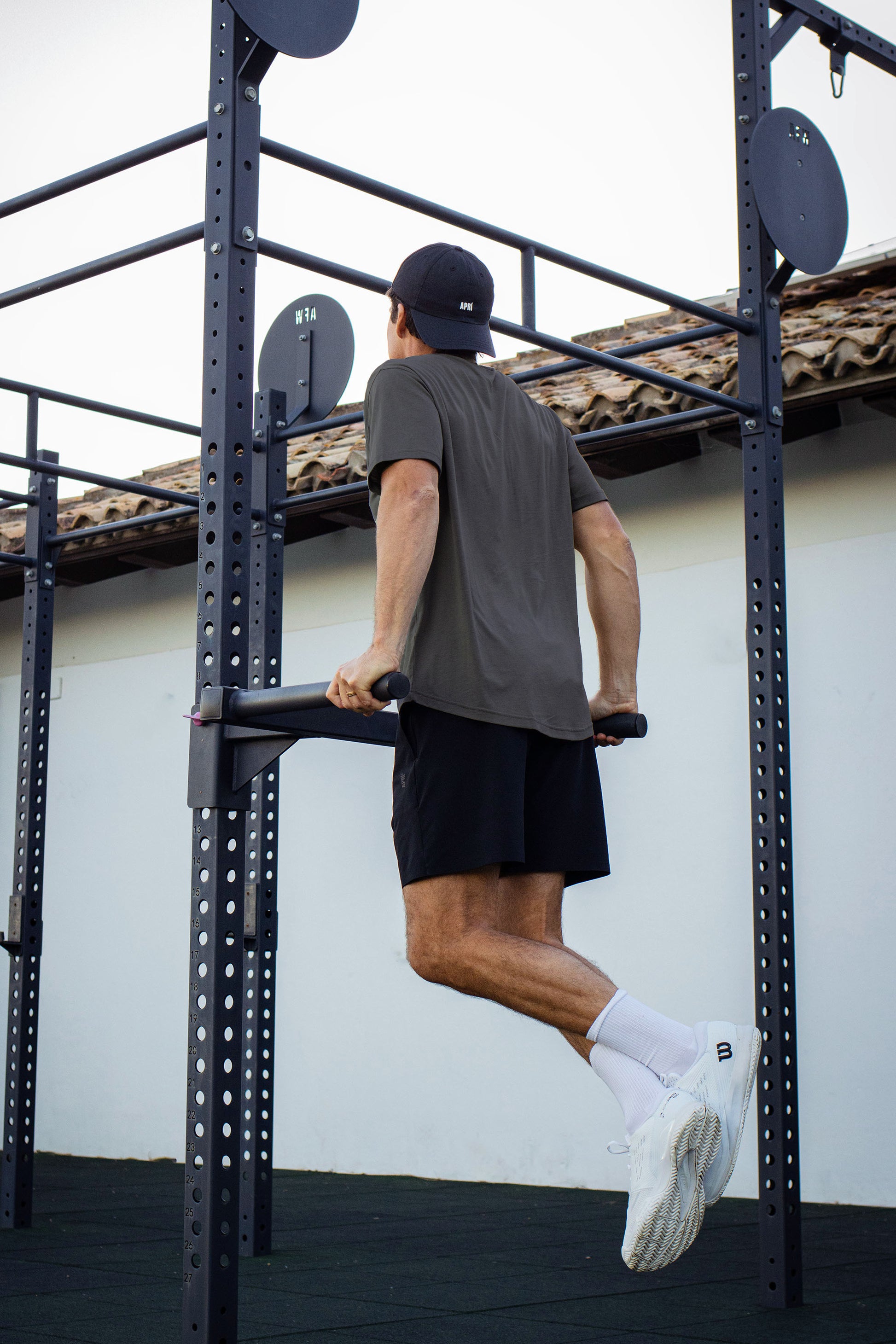 Person using pull-up bars on an outdoor fitness structure in asphalt lyocell t-shirt