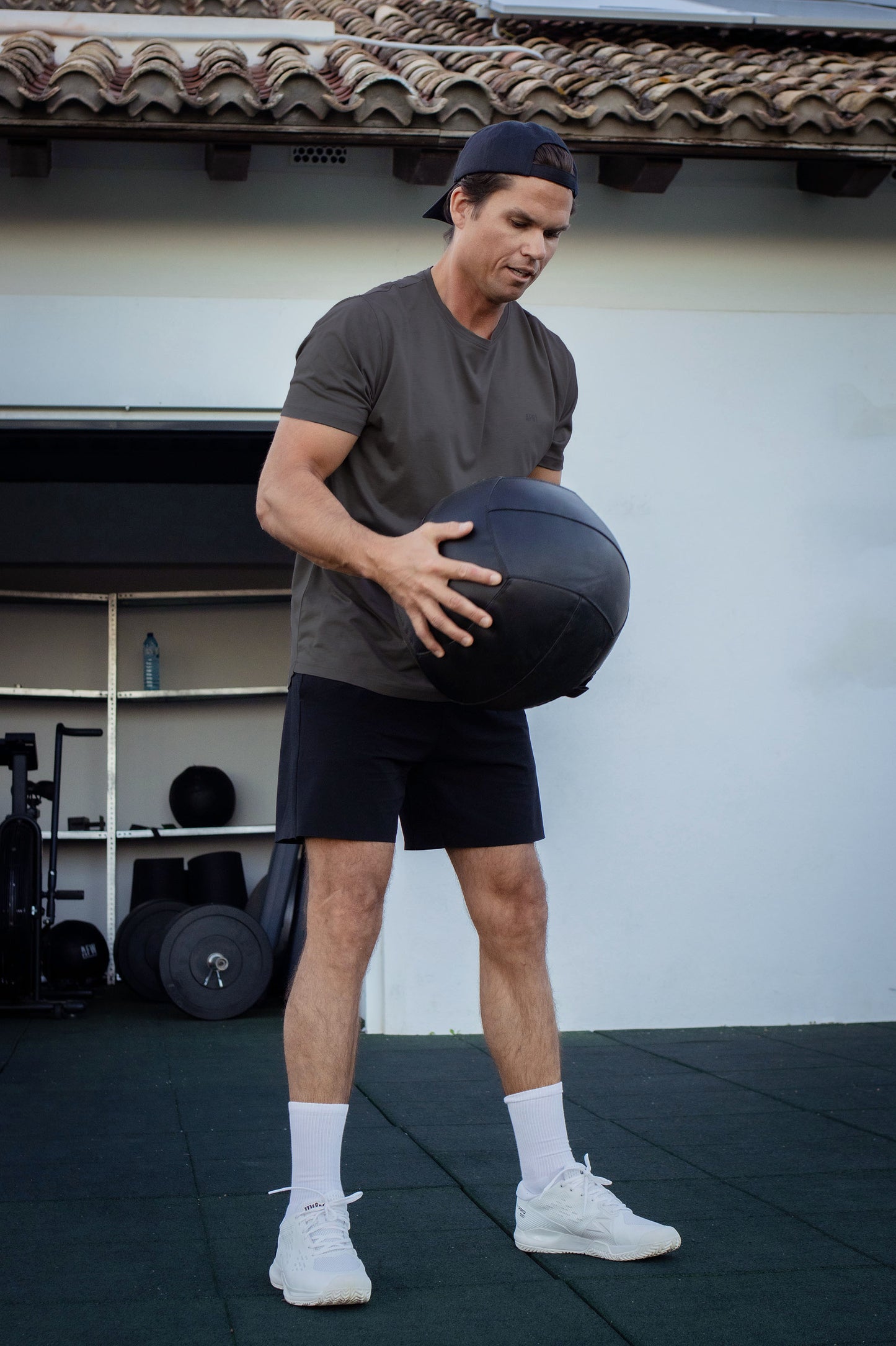 Man holding a medicine ball in an outdoor gym setting in lyocell asphalt t-shirt