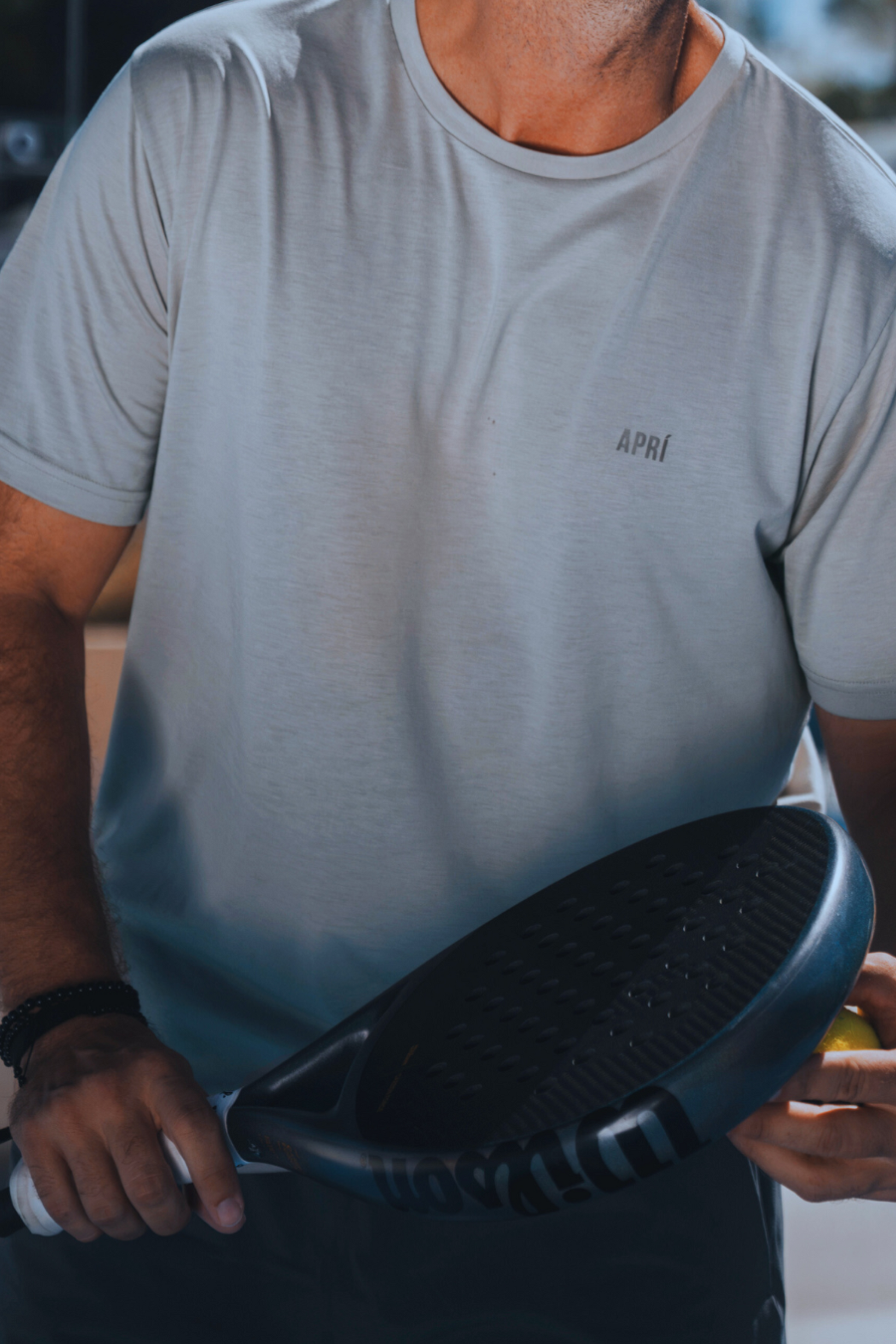 Man wearing a gray t-shirt with 'APRI' logo holding a black disc.