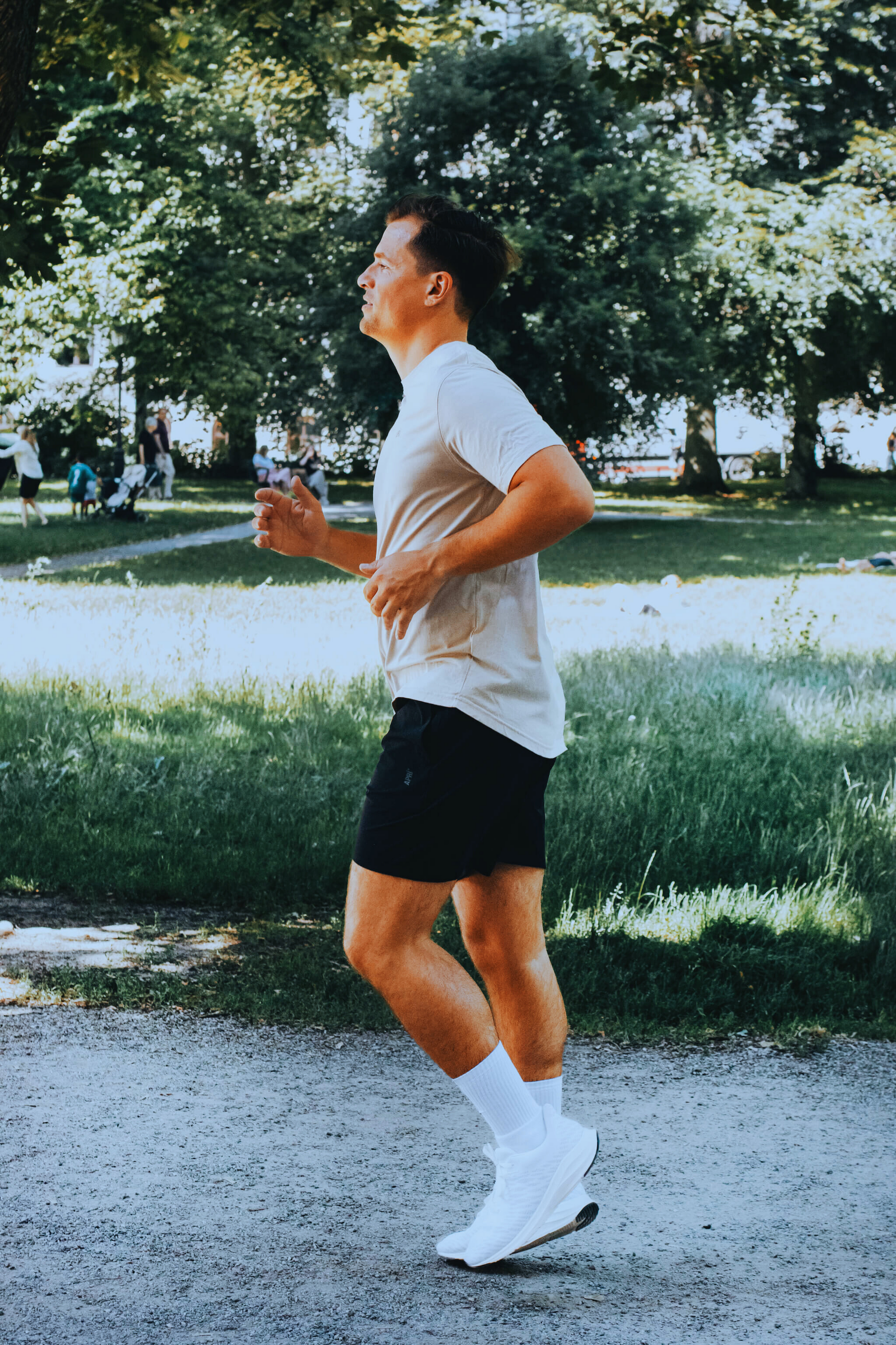 Person running in a park with trees and a lake in the background